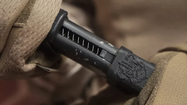 Operador con guantes tácticos empuñando una secundaria con la base de cargador Glock